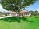 Charming home with well-maintained lawn, mature tree, and neutral stucco exterior with tan accents at 2256 Margarita Dr, The Villages, FL 32159