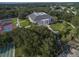 Aerial view of the community clubhouse, tennis courts, and shuffleboard, framed by lush greenery at 25524 Maurepas Ln, Leesburg, FL 34748