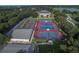 Expansive aerial view of tennis and shuffleboard courts, community building, and parking area at 25524 Maurepas Ln, Leesburg, FL 34748
