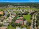 Aerial view of the community featuring tennis courts, surrounding homes, and mature trees at 25524 Maurepas Ln, Leesburg, FL 34748