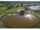 Aerial view of a community baseball field, pond, and surrounding green space with golf course and single Gathering homes at 25524 Maurepas Ln, Leesburg, FL 34748
