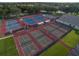 Aerial view of a complex featuring multiple tennis courts with both blue and gray surfaces at 25524 Maurepas Ln, Leesburg, FL 34748