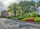Community entryway with lush landscaping, flowers, and palm trees adding to the curb appeal at 25524 Maurepas Ln, Leesburg, FL 34748