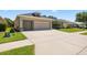 A single-story home features an expansive concrete driveway leading to the two-car garage at 25524 Maurepas Ln, Leesburg, FL 34748