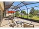 Screened lanai with a dining table, chairs, and views of the manicured backyard and landscaping at 25524 Maurepas Ln, Leesburg, FL 34748