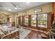 Cozy living room with hardwood floors, a ceiling fan, and large windows offering lots of natural light at 25524 Maurepas Ln, Leesburg, FL 34748