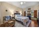 Cozy bedroom with hardwood floors, large window with blinds, a comfortable bed and a leather recliner at 25524 Maurepas Ln, Leesburg, FL 34748