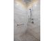 Newly tiled shower with a rainfall shower head, handheld sprayer, grab bar, and unique tile flooring at 25524 Maurepas Ln, Leesburg, FL 34748