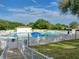 Community swimming pool with bright blue water, surrounded by a white fence, lounge chairs, and umbrellas at 25524 Maurepas Ln, Leesburg, FL 34748