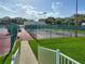 View from steps to community tennis courts surrounded by green fencing and lush green grass at 25524 Maurepas Ln, Leesburg, FL 34748