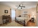 Well-lit bedroom featuring a wrought iron bed frame, hardwood floors, and a vintage desk at 27022 Racquet Cir, Leesburg, FL 34748
