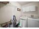 Laundry room with modern appliances, storage cabinets, and a wire shelf for organization at 27022 Racquet Cir, Leesburg, FL 34748