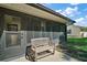A view of the screened-in lanai/patio with a wooden bench and a door leading into the house at 27022 Racquet Cir, Leesburg, FL 34748