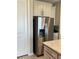 Close-up of a modern stainless steel refrigerator in a kitchen with white cabinets and granite countertops at 2786 Top Hill Ct, Minneola, FL 34715