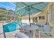 Relaxing screened-in pool area featuring a covered patio with comfortable seating and lush green surroundings at 2855 Picadilly Cir, Kissimmee, FL 34747