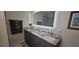 Bathroom featuring double sinks with granite counters, a lighted mirror, and a tiled walk-in shower at 3096 Maywood Ct, The Villages, FL 32162