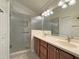 Bright bathroom with double sink vanity, granite countertops, decorative lighting and glass enclosed shower at 3325 Archer Ave, The Villages, FL 32162