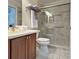 Stylish bathroom featuring granite counters, wood cabinets, tiled floors, and a glass shower with grab bars at 3325 Archer Ave, The Villages, FL 32162