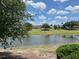 Scenic view of home exterior overlooking pond and lush green lawn on a sunny day at 3325 Archer Ave, The Villages, FL 32162
