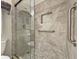 Close up of frameless glass shower door with grab bar, shower niche, and granite tile at 3325 Archer Ave, The Villages, FL 32162