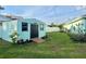 Aqua-colored shed, features a black door, two windows, and is surrounded by a lush green lawn at 33635 Jeffery Ct, Leesburg, FL 34788