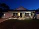 Charming single-story home with a well-lit front porch and manicured lawn, showcasing curb appeal at twilight at 33635 Jeffery Ct, Leesburg, FL 34788