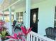 Welcoming covered front porch with red Ti plants and Adirondack chairs for relaxing outdoors at 33635 Jeffery Ct, Leesburg, FL 34788