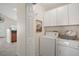 Functional laundry room with white washer, dryer, white cabinets, and a decorative touch at 33635 Jeffery Ct, Leesburg, FL 34788