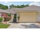Beige two car garage with neutral siding and walkway to the front door surrounded by lush landscaping at 340 Juniper Way, Tavares, FL 32778