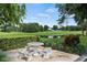 Outdoor seating area with stone table and benches overlooking a pond with lush greenery and trees at 340 Juniper Way, Tavares, FL 32778