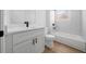 Bathroom featuring white cabinets with black hardware, dual vanity, toilet and tub at 3978 Sw 151St St, Ocala, FL 34473