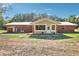 Exterior view of a brick house with a metal roof, connected sunroom, and a spacious backyard at 42116 E Lakeview Dr, Altoona, FL 32702