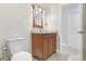 Bathroom vanity with decorative mirror and lighting, a toilet, and an open doorway at 42116 E Lakeview Dr, Altoona, FL 32702