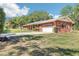 Side view of a red brick house with a driveway and a well-maintained lawn at 42116 E Lakeview Dr, Altoona, FL 32702