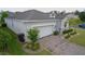 Home featuring a brick driveway, two-car garage, complemented by lush greenery and elegant stone detailing at 496 Brunswick Dr, Davenport, FL 33837