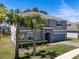 Two-story home featuring a gray exterior with stone accents, blue shutters, and palm trees enhancing curb appeal at 524 Avila Pl, Howey In The Hills, FL 34737
