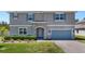 Exterior showcasing stone accents, a well-manicured lawn, a driveway, and vibrant blue shutters at 524 Avila Pl, Howey In The Hills, FL 34737