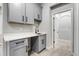 Well-lit laundry room with gray cabinets, black hardware, and a modern black faucet at 524 Avila Pl, Howey In The Hills, FL 34737