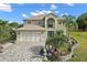 Inviting two-story home features a lush landscaped yard, two-car garage and stone driveway at 54 Andora Ct, Kissimmee, FL 34758