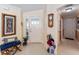 Inviting foyer featuring tile flooring, a decorative bench, and a beautifully decorated wall with a mirror and clock at 648 Mission Hills Trl, The Villages, FL 32162