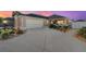 Charming home featuring a well-manicured lawn, neutral stucco, and a two-car garage with an extended, patterned concrete driveway at 648 Mission Hills Trl, The Villages, FL 32162