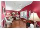 Comfortable living room with hardwood floors, and bright red walls, and plantation shutters on the windows at 648 Mission Hills Trl, The Villages, FL 32162