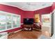 Bright living room with red accent wall, modern shutters, and wood flooring at 648 Mission Hills Trl, The Villages, FL 32162