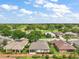 An aerial view of several homes and mature trees showcases the surrounding green golf course under a beautiful blue sky at 7034 Pine Hollow Dr, Mount Dora, FL 32757