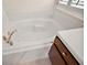 Large white soaking tub with tile surround and a vanity with storage nearby at 7034 Pine Hollow Dr, Mount Dora, FL 32757