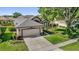 Aerial view of a well-manicured home, showcasing a two-car garage, lush landscaping, and an inviting driveway at 7034 Pine Hollow Dr, Mount Dora, FL 32757
