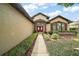 Eye-level front entrance showing red double-doors, shutters, and decorative shrubs lining the walkway at 7034 Pine Hollow Dr, Mount Dora, FL 32757