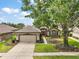 Charming single-story home featuring manicured landscaping and a welcoming red double-door entrance at 7034 Pine Hollow Dr, Mount Dora, FL 32757