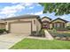 Charming home featuring manicured landscaping, a two-car garage, and a welcoming red double-door entrance at 7034 Pine Hollow Dr, Mount Dora, FL 32757