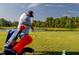 Personal playing golf with a golf bag in front and a pond in the distance surrounded by greenery at 7034 Pine Hollow Dr, Mount Dora, FL 32757